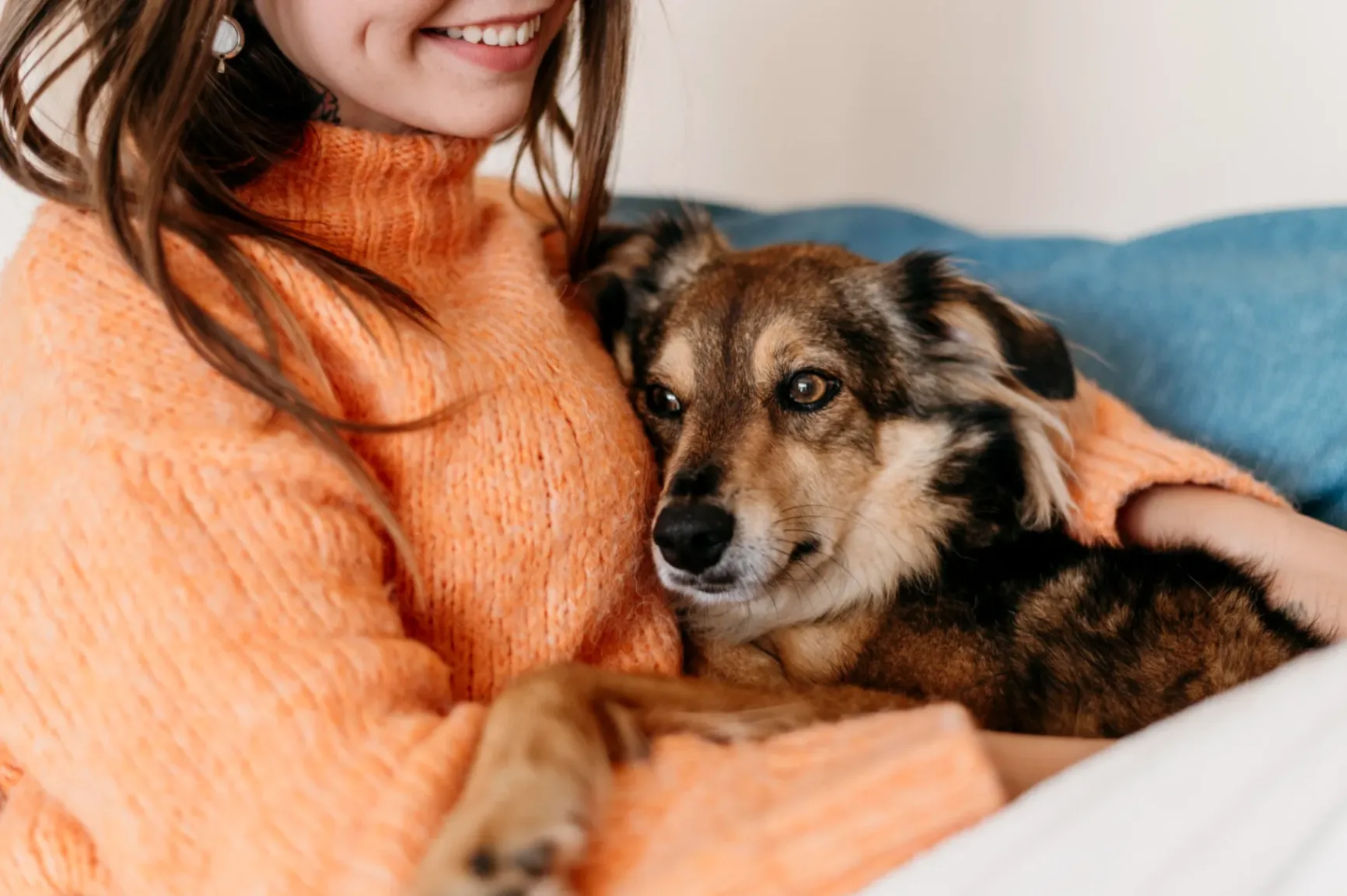 A woman sitting on a bed with a dog.